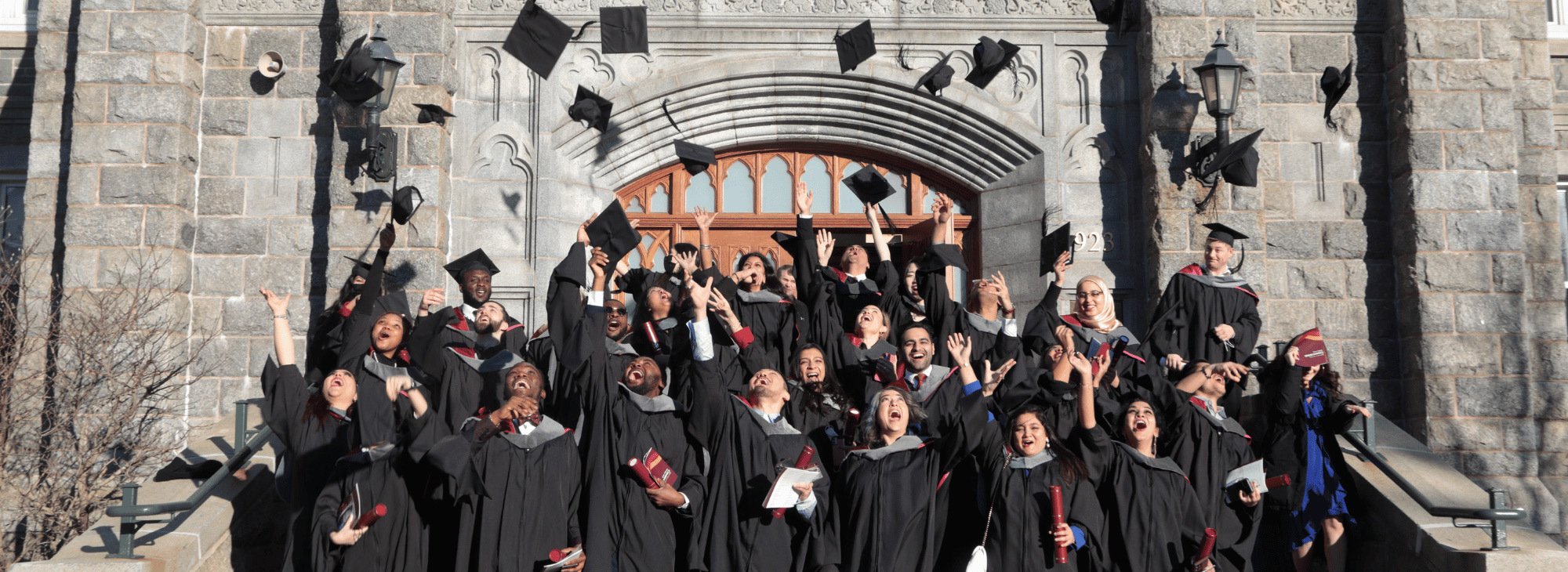 A group of graduates toss there caps on the steps of McNally building