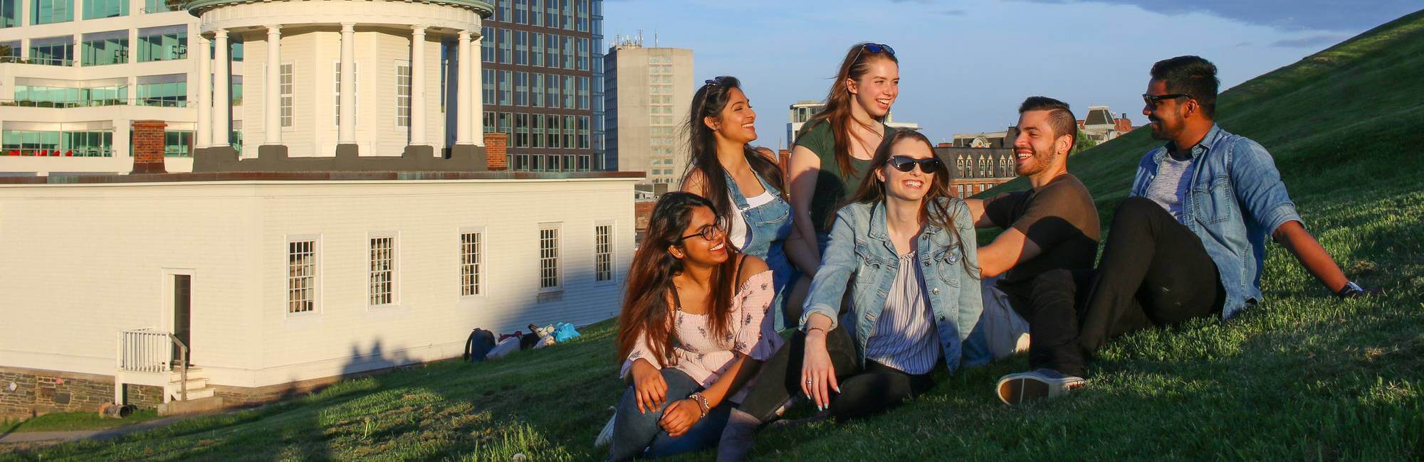 Students sitting together on a grassy slope in Halifax, Nova Scotia.