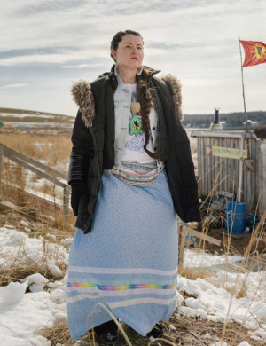 A woman standing outside, with snow on the ground in a rural area