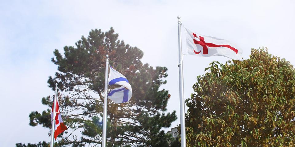 The Mi’kmaq Grand Council flag flying in front of the McNally building with the Nova Scotian and Canadian flags